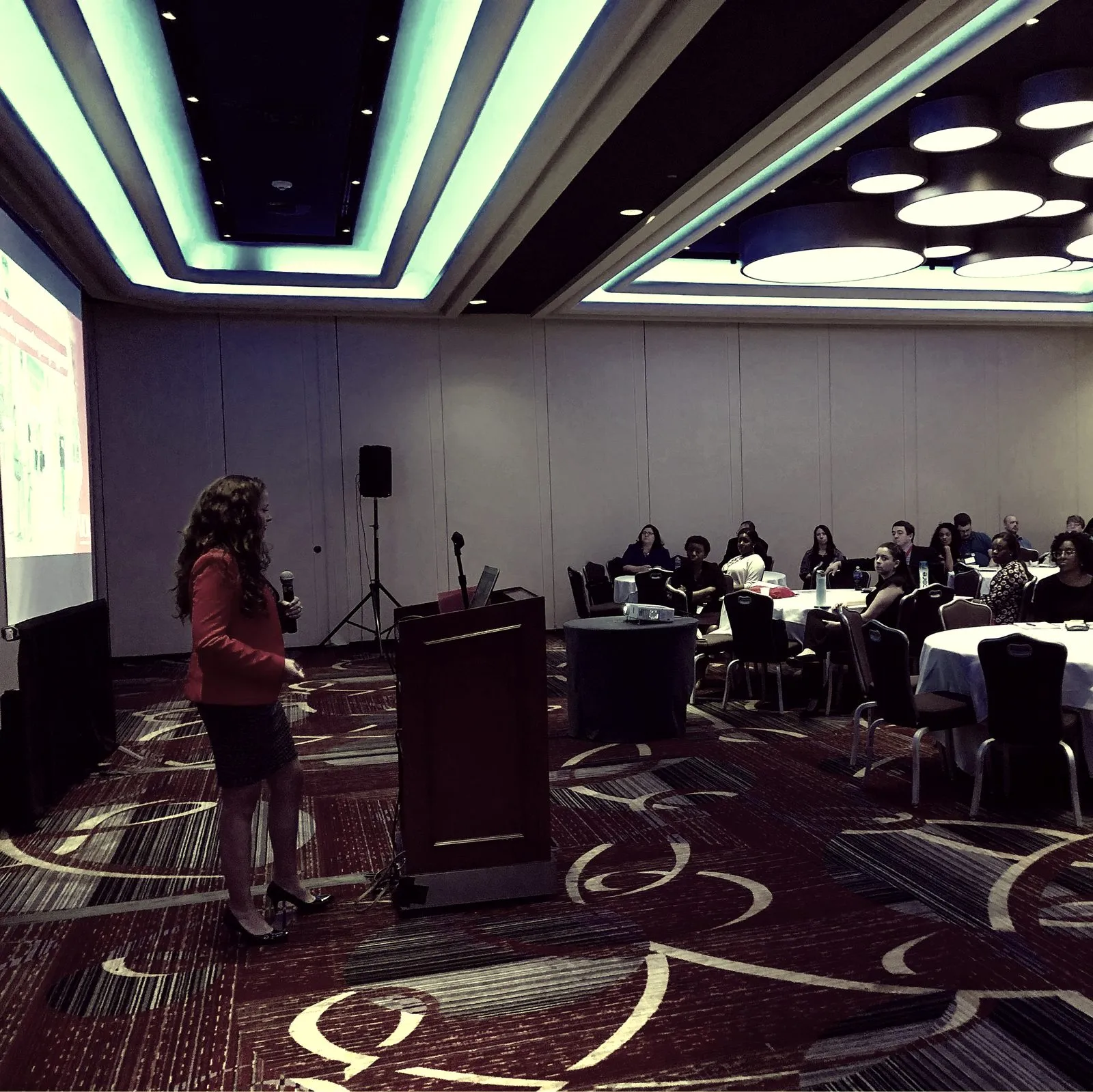 Ruth Dickson Eddy presenting from a podium to a seated conference audience.