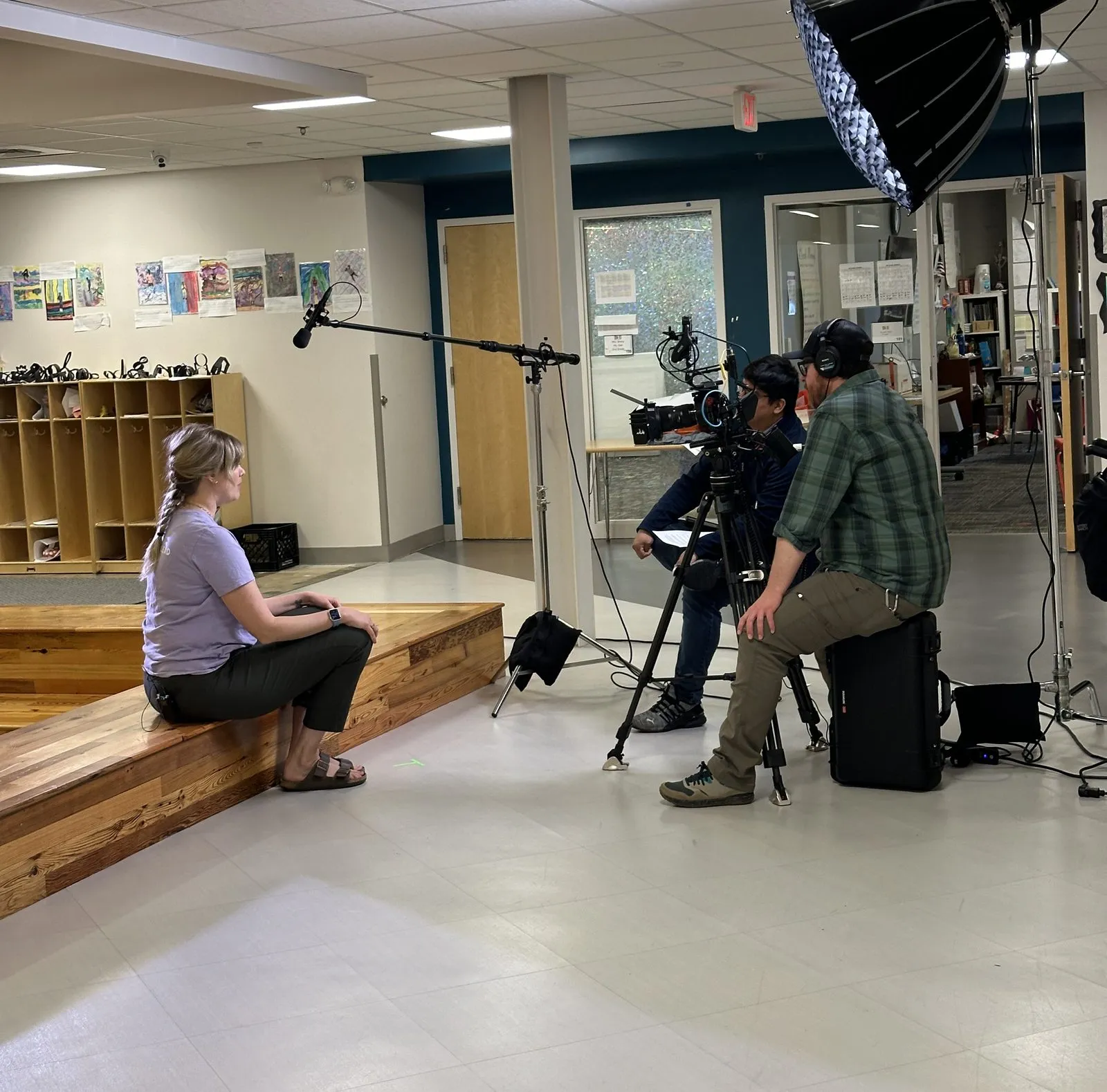 A film crew with camera, boom microphone, and lighting recording an interview on location.